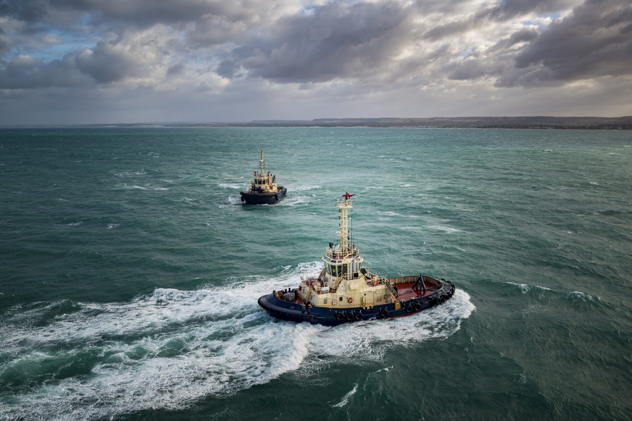 A high angle shot of investigative boats sailing in the turquoise ocean under the cloudy sky